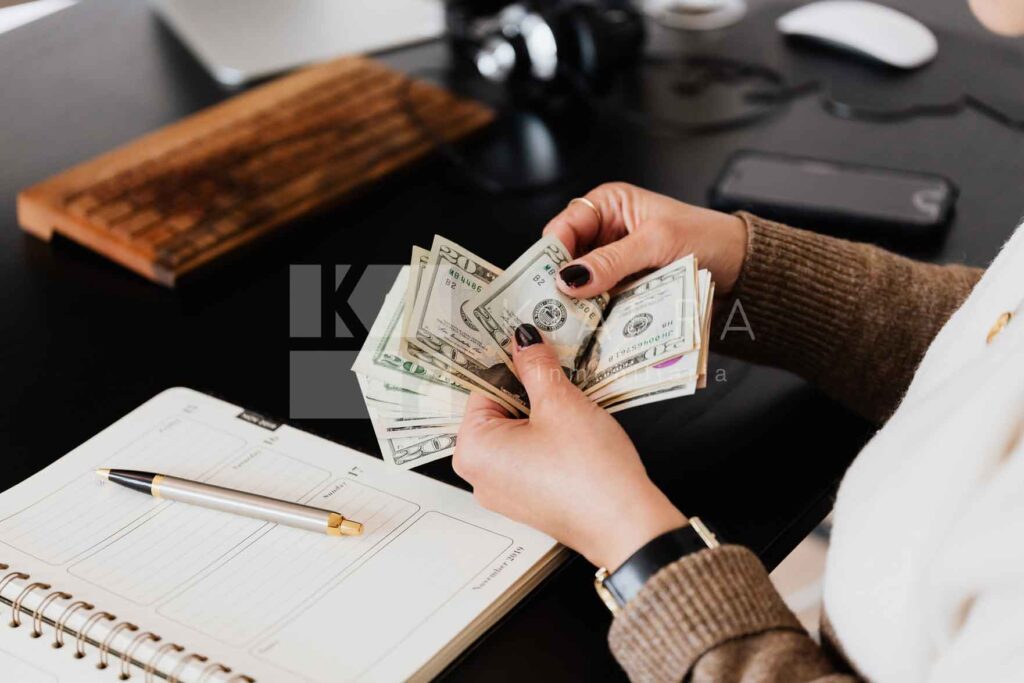 Persona contando billetes y la marca de agua de inmobiliaria KIAFRA