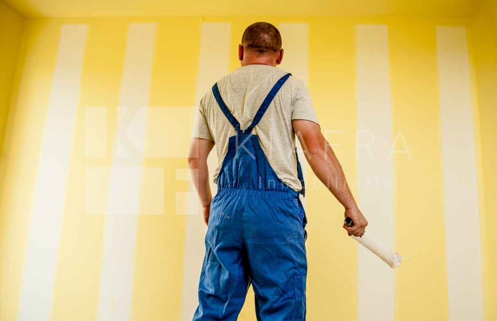 Pintor observando una pared amarilla y al principio la marca de agua de Inmobiliaria KIAFRA