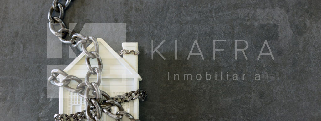 Casita de plástico enredada entre cadenas y en frente la marca de agua de Inmobiliaria KIAFRA