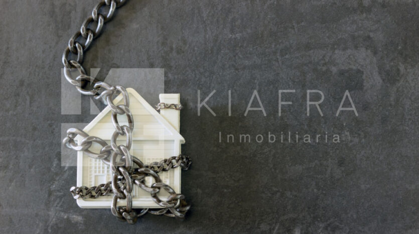 Casita de plástico enredada entre cadenas y en frente la marca de agua de Inmobiliaria KIAFRA