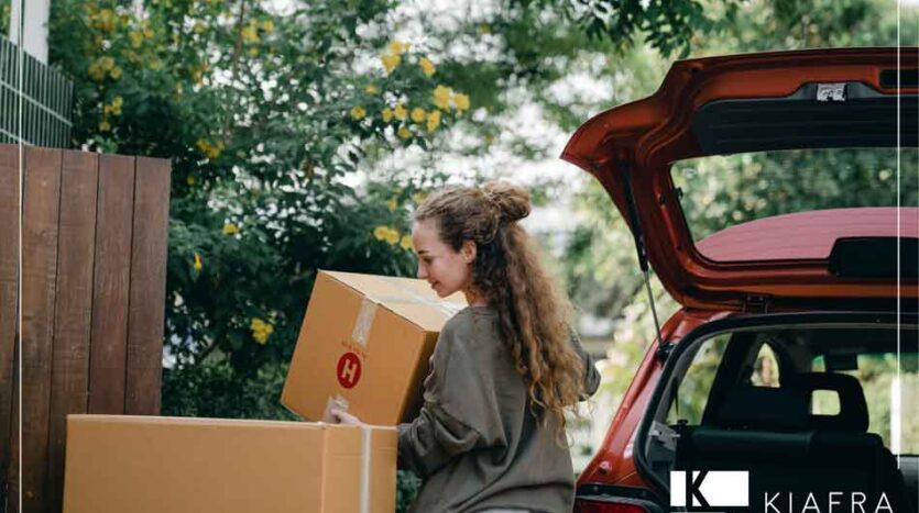 Mujer subiendo cajas de su mudanza a su camioneta y el marco de Inmobiliaria KIAFRA