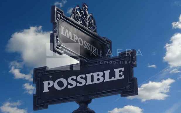 Letrero que muestra dos caminos, unos que dice "Impossible" y otro que dice "Possible" con la marca de agua de Inmobiliaria KIAFRA